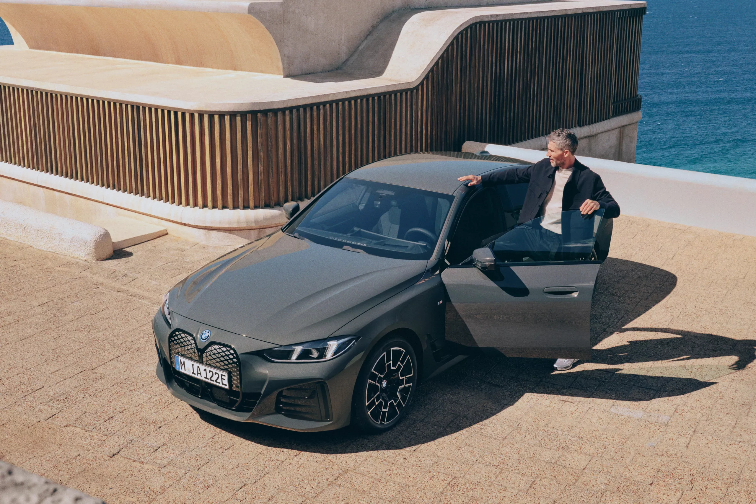 BMW i4 garée devant une maison contemporaine, vue trois-quarts avant