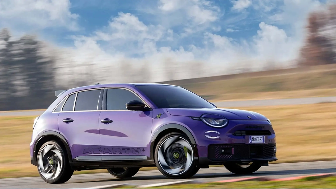 Vue avant dynamique de l’Abarth 600e électrique sur route.
